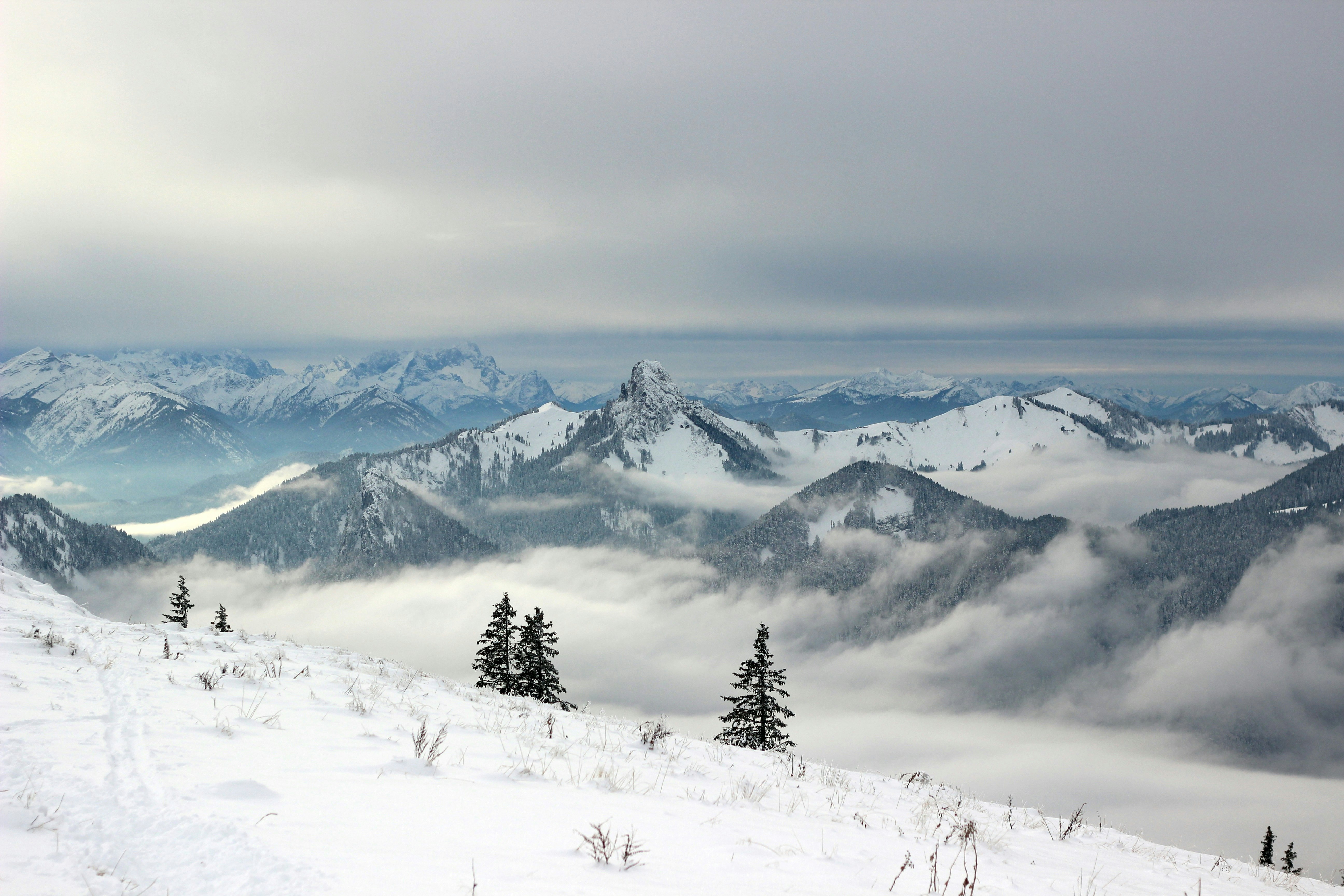 snow covered mountains under grey clouds
